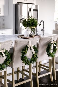 a kitchen island decorated with wreaths and greenery