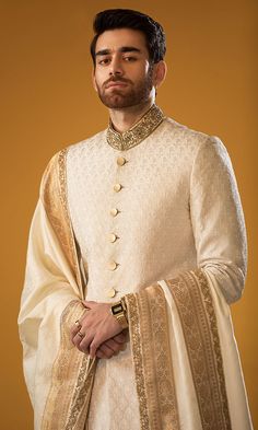 a man with a beard wearing a white and gold outfit