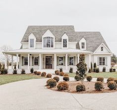 a large white house with lots of windows and bushes in front of the entrance to it