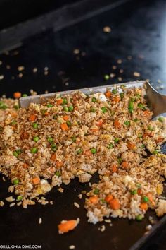 a pan filled with rice and veggies on top of a counter next to a spatula