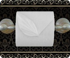 an image of a white paper towel on a black and gold wall mounted tissue dispenser