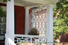 a porch with white railings and plants on the front steps, next to a red brick building