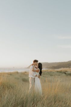 a couple kissing in tall grass by the ocean