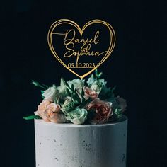 a white cake topped with flowers and a gold heart topper that says happily married