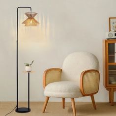 a white chair sitting next to a lamp on top of a wooden stand in a living room