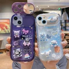 two people holding up cell phones with cartoon stickers on the back, and one is wearing