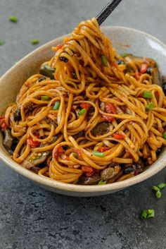 a bowl filled with noodles and vegetables on top of a table