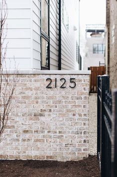 a brick wall with the number 2165 written on it in front of a house