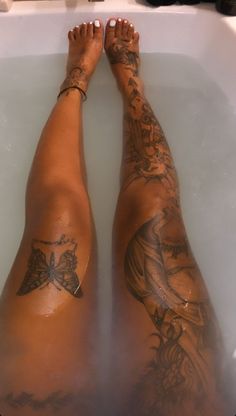 a person with tattoos sitting in a bathtub