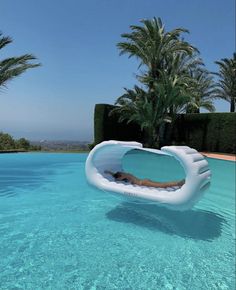 an inflatable swimming pool with a person laying on the side and palm trees behind it