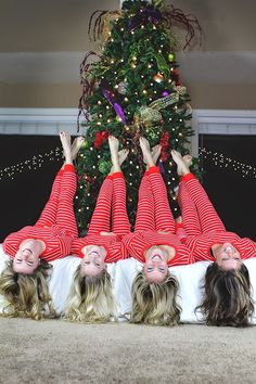 four women laying on the floor in front of a christmas tree with their hands up