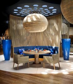 a restaurant with round tables and blue vases on the wall, in front of a circular wooden screen