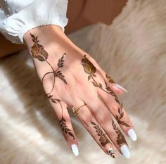 a woman's hand with hennap and flowers painted on her left arm