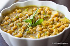 a white bowl filled with soup and garnished with green leafy garnish