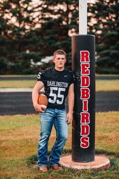 a man holding a football standing next to a pole