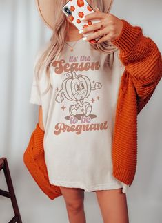 "🎃 This retro \"Tis the Season to be Pregnant\" shirt is the perfect way to announce your fall pregnancy. With Halloween and Thanksgiving just around the corner, this maternity tee is a fun and festive way to share the news with friends and family. Surprise your wife or loved one with this unique baby reveal gift and watch her glow with joy. Celebrate your growing family this fall with this adorable fall pregnancy announcement shirt. 👕 PRODUCT INFO The Bella + Canvas shirts are super soft and comfy! They fit true to size so choose your usual size for the best fit! If you would like to wear this shirt for your entire pregnancy, I recommend going up a size! The solid colored shirts are 100% cotton. And the heather colors and Solid Black Blend are 52% cotton, 48% polyester. ✏️ DESIGN Design Football Pregnancy Announcement, Second Pregnancy Announcements, Gifts For Expecting Dads, Fall Pregnancy Announcement, Book Nerd Shirts, Halloween Pregnancy Announcement, Pregnant Halloween, Fall Maternity, Pregnancy Announcement Shirt