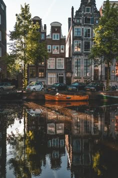 there is a small boat on the water in front of some buildings and parked cars