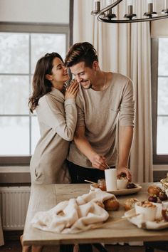 a man and woman standing in front of a table with food