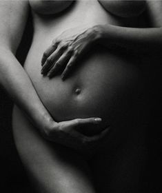 a black and white photo of a pregnant woman's belly with her hands on her stomach