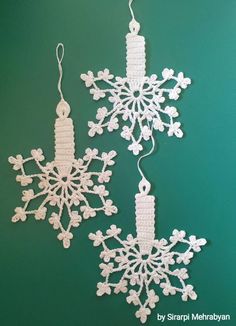 crochet snowflake ornaments hanging on a green wall