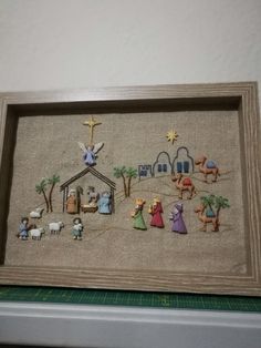 a cross stitch nativity scene is displayed in a frame