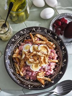 a bowl filled with meat and eggs on top of a table next to utensils