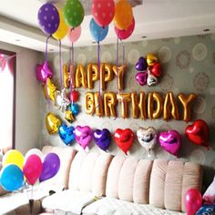 a living room filled with lots of balloons on the wall and a happy birthday sign above it