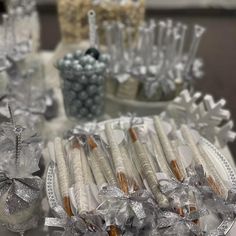 there are many silver and white items on the trays at this table, including candy canes