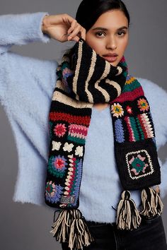 a woman wearing a scarf with tassels is posing for the camera while holding her hand on her head