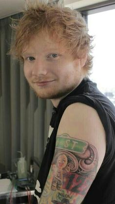 a man with a tattoo on his arm posing for a photo in front of a window