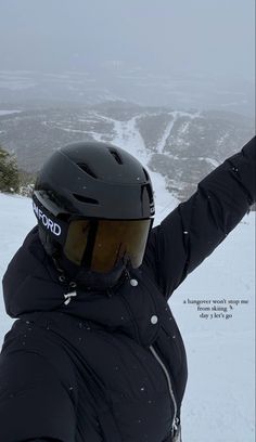 a person wearing a helmet and holding their arms up in the air while standing on top of a snow covered mountain