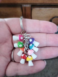 a person is holding a bunch of small charms in their hand and they are all different colors