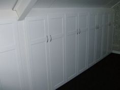 a room with white cupboards and black carpeted flooring on the side of it