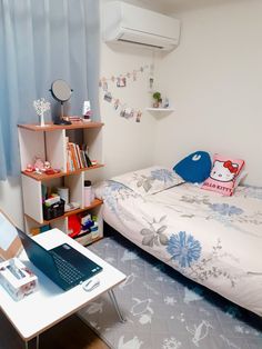 a small bedroom with a bed, desk and laptop on the table in front of it