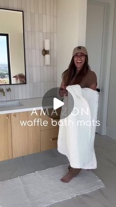 a woman standing in a bathroom holding a towel