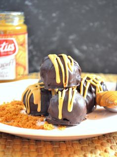 three chocolate covered desserts sitting on top of a white plate next to a jar of peanut butter