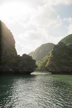 the sun shines brightly on some mountains and cliffs along the water's edge