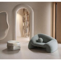 a white room with a chair and mirror on the wall, next to it is an oval shaped sculpture