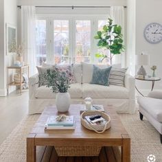 a living room filled with furniture and a clock on the wall above it's windows