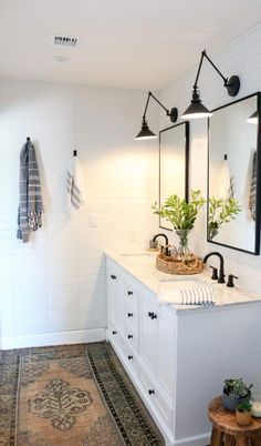 a bathroom with two sinks, mirrors and plants on the counter top in front of it