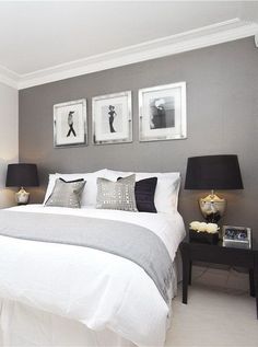 a bedroom with gray walls and white bedding, two framed pictures on the wall