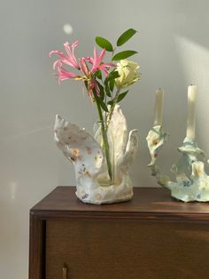 two vases with flowers in them sitting on a wooden table next to a wall