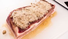 a piece of meat sitting on top of a white plate covered in crumbs