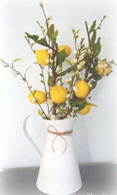 a white pitcher filled with lemons and baby's breath