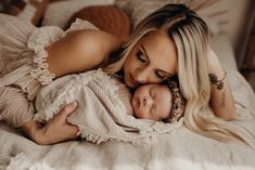 a woman laying on top of a bed holding a baby