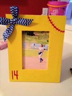 a yellow frame with a baseball on it and a blue ribbon tied around the edge