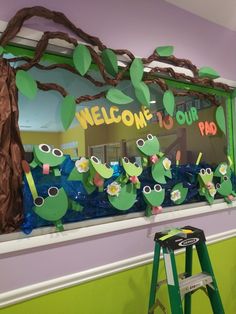 a classroom display with paper cut out of frogs on the windowsill and welcome to our pad