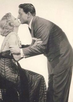 an old black and white photo of a man kissing a woman