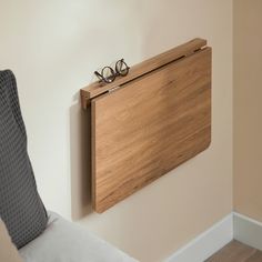 a pair of glasses sitting on top of a wooden shelf next to a bed with pillows