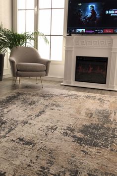 a living room with a large rug, chair and television on the fireplace mantel